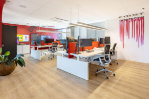 Stijlvolle kantoorruimte met rode en witte accenten en een kunstzinnige wanddecoratie.