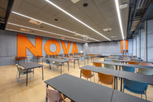 : Lesruimte van Nova College met groot oranje "NOVA" logo en moderne inrichting
